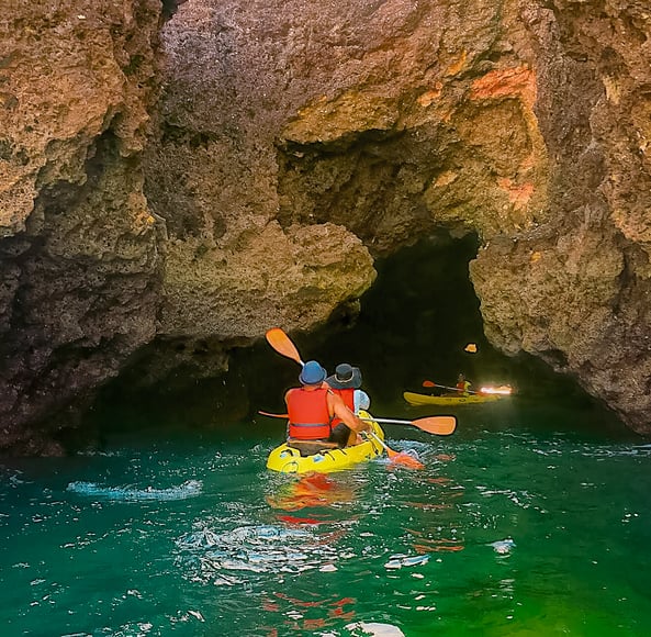 Muslim travel couple kayaking into dark cave