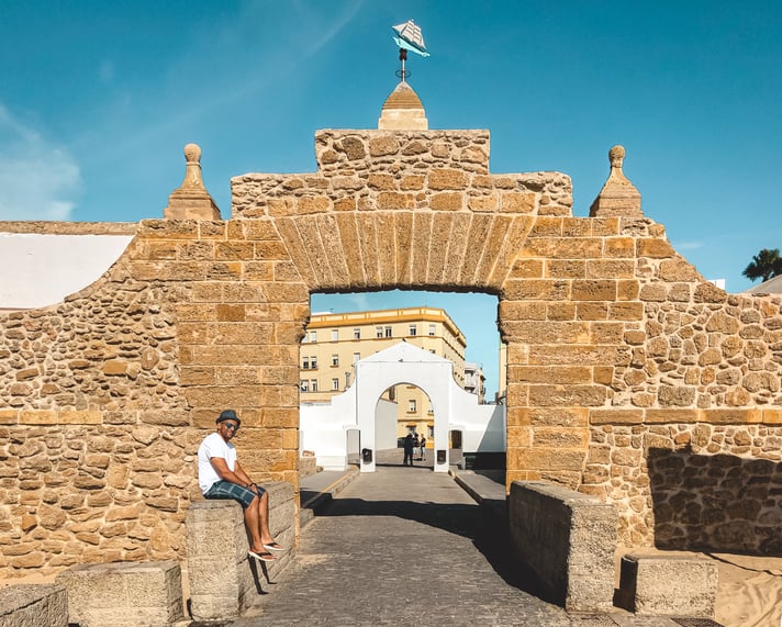 Muslim man sitting on a rocks at the entrance to La Caleta beach in Cadiz