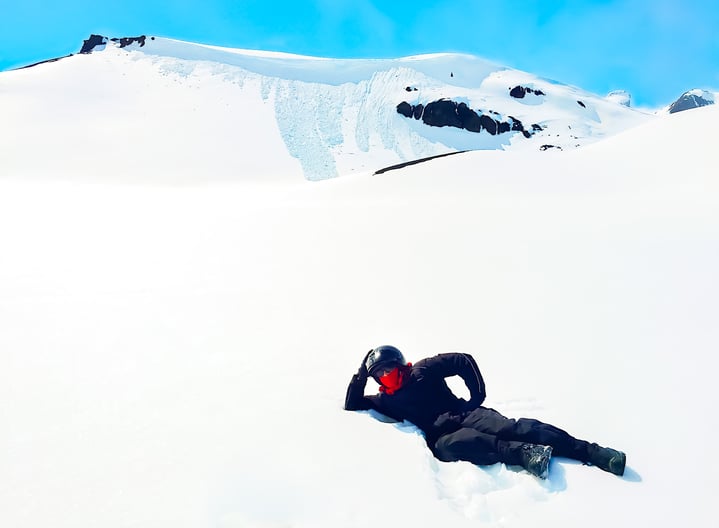 Man in black snow suit posing on snowy glacier