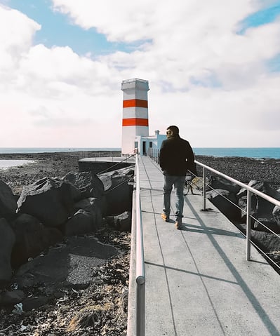 Man walking to red striped Gardur lighthouse