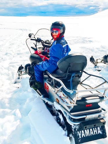 Muslim travel blogger sitting on snowmobile on glacier