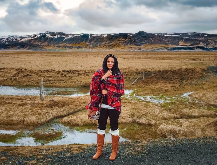 Muslim woman wearing red scarf in front of Icelandic mountains
