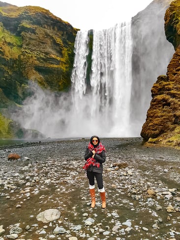 Muslim woman standing in front of Skogafoss waterfall