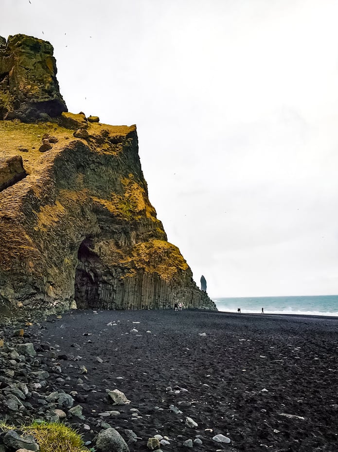 Moss covered basalt cliffs on black sand beach Iceland