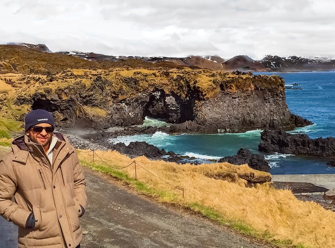 Man next to rock caves and ocean