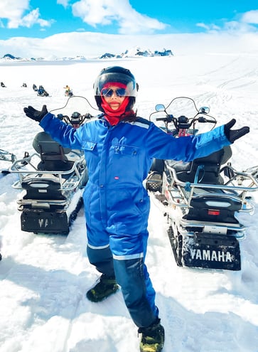 Muslim woman posing on glacier beside snowmobiles