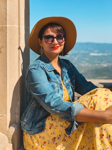 Muslim travel blogger in yellow dress sitting in arch on Montserrat