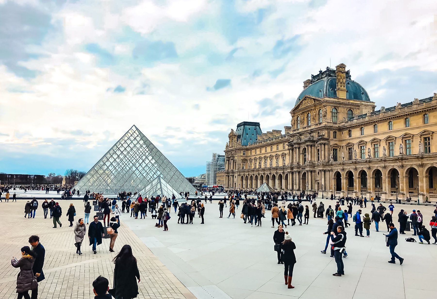 Louvre Museum's glass pyramid surrounded by people