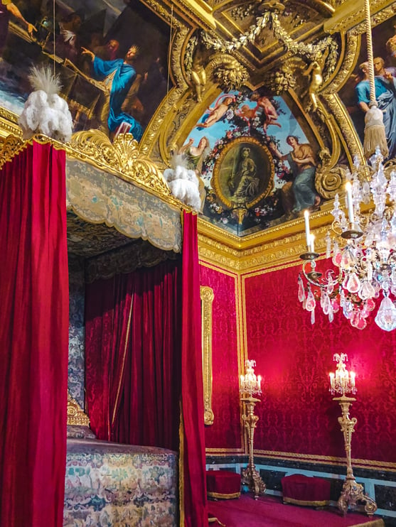 Four poster bed and mural ceiling inside Palace of Versailles