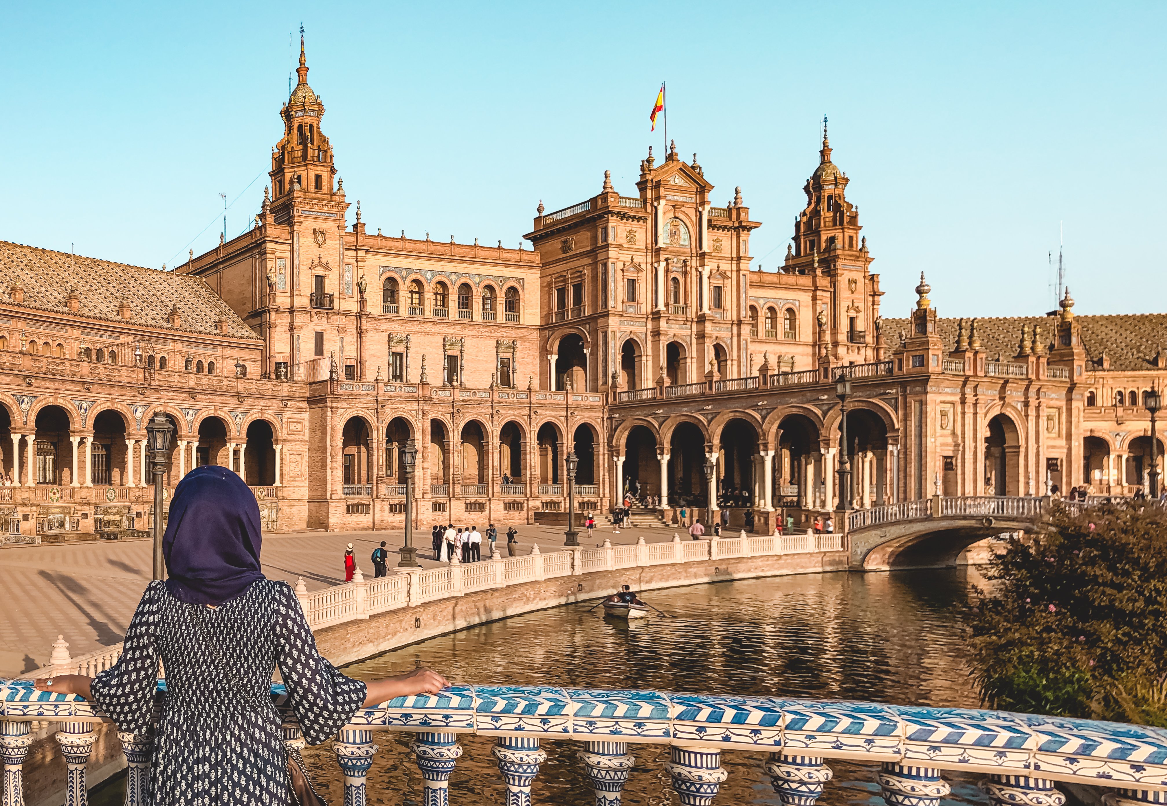 Muslim woman wearing blue dress standing on bridge over canal at Plaza de Espana Seville