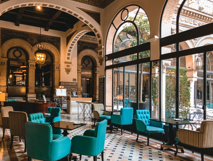 Turquoise chairs face arched windows and courtyard in hotel Alfonso