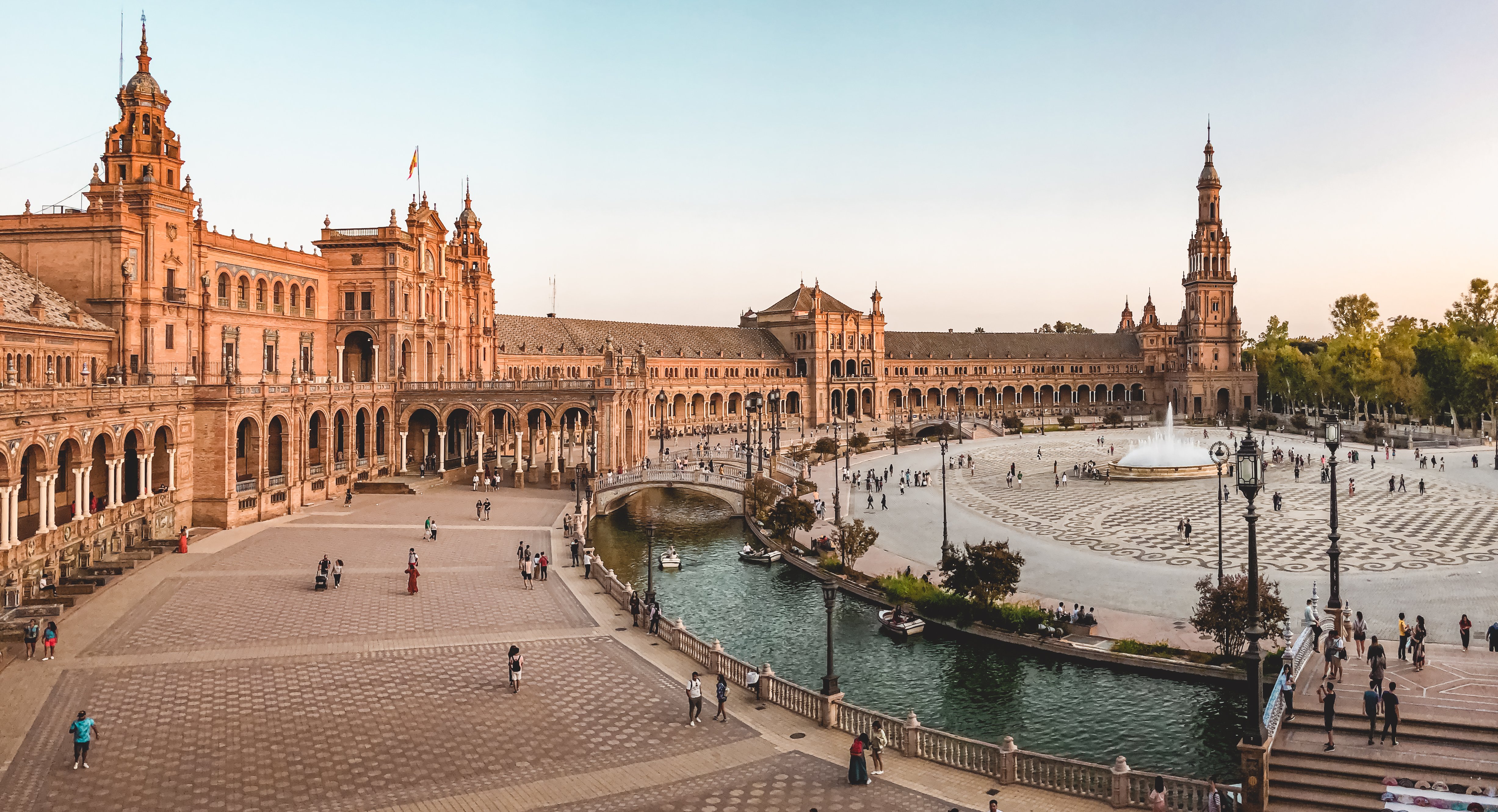 Semi-circular panorama of orange-tinged Plaza de Espana Seville