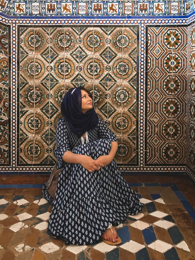 Muslim woman seated looking at tiled walls in Seville Alcazar